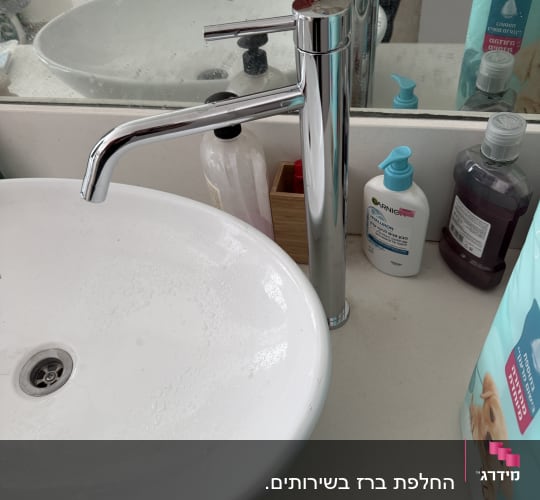 כיור וברז בחדר אמבטיה עם מוצרי טיפוח